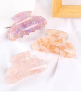 Primo piano dettagliato di tre mollette per capelli marmorizzate traslucide pastello.