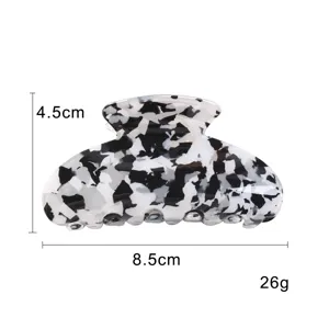 Molla per capelli geometrica in acrilico traforato bianco e nero, dettaglio elegante.