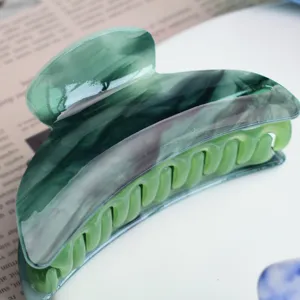Molla per capelli in acrilico verde con elegante trama marmo, dettaglio media misura.