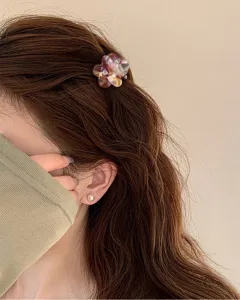 Vista dettagliata di una mini molletta per capelli a fiore, design traslucido colorato per uso quotidiano.