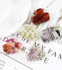 Dettaglio mini molletta per capelli con motivi geometrici, tartaruga e design a quadri.