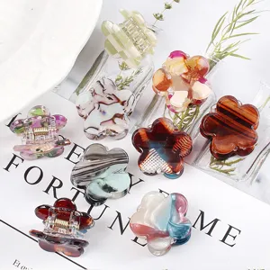 Dettaglio di mini mollette per capelli a forma di fiore, accessori colorati in acetato.