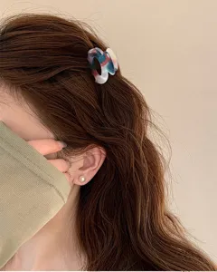 Primo piano dettagliato della mini molletta per capelli geometrica colorata sui capelli.