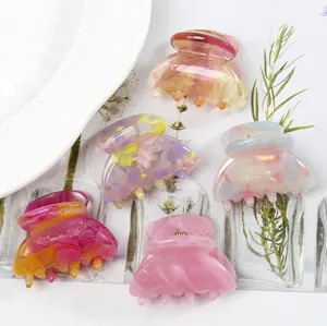 Primo piano dettagliato di mini mollette per capelli in acetato con fantasia marmorizzata.