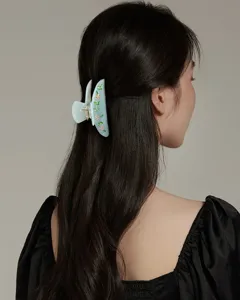 Dettaglio ravvicinato della molletta per capelli in acetato azzurro con fiori in strass brillanti.