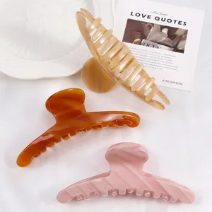 Detail shot of elegant acetate hair claws in chic neutral and pink tones, perfect for styling.