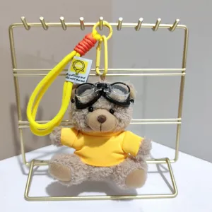 Cute pilot teddy bear plush keychain with goggles, yellow hoodie and lanyard bag charm.