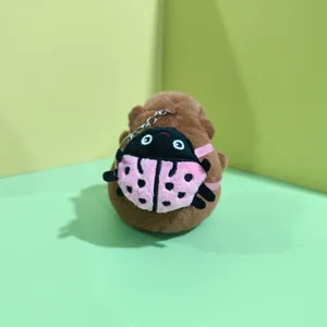 Close-up of cute capybara plush toy with ladybug backpack and metal keychain detail.