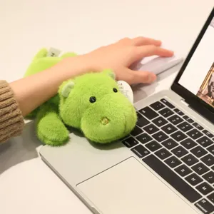 Cute green plush toy desktop companion close-up, soft furry doll resting on computer keyboard.