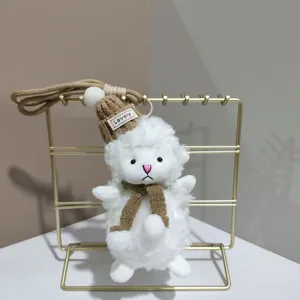 Gros plan détaillé du joli porte-clés en peluche mouton blanc avec bonnet et écharpe tricotés.