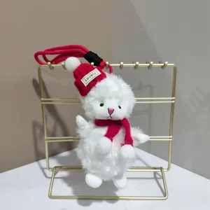 Gros plan du mignon pendentif poupée mouton en peluche blanche avec bonnet rouge.