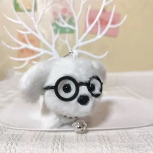 Close-up van een schattige witte pluche puppy sleutelhanger met een ronde bril en klein belletje.