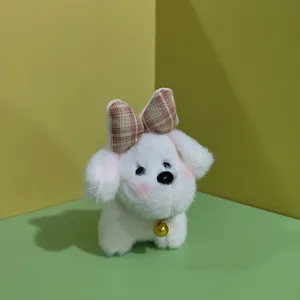 Dettaglio del portachiavi in peluche di cucciolo bianco carino con fiocco a quadretti e campanello d'oro.