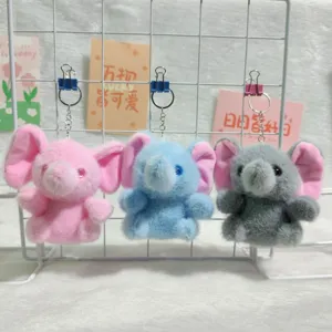 Detailed view of cute plush elephant keychains in pink, blue and gray, hanging on grid shelf.