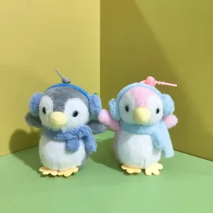 Primo piano di simpatici portachiavi in peluche di pinguino con cuffie e sciarpe colorate.