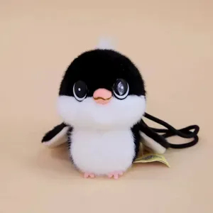 Cute small bird plush toy pendant detail, soft fluffy black and white toy with hanging cord.