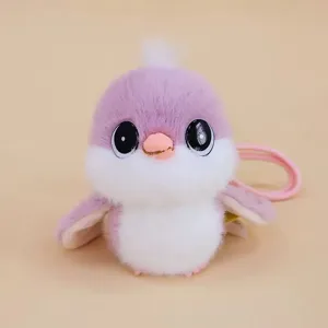 Close-up detail of cute purple and white titmouse plush doll pendant with shiny big eyes.
