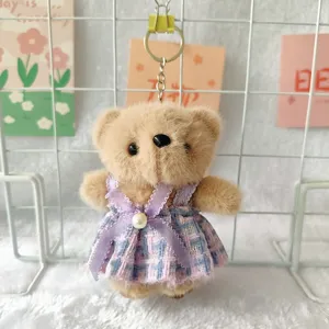 Close-up of cute plush bear keychain wearing a purple plaid dress, soft texture detail.