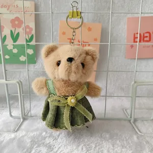 Cute plush teddy bear keychain detail, green corduroy dress pendant, fluffy soft toy charm.
