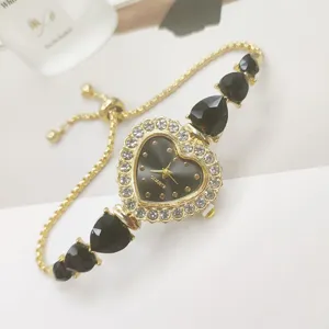 Detaillierte Aufnahme einer goldenen Herz-Quarzuhr mit schwarzen Kristallanhängern und Armband.