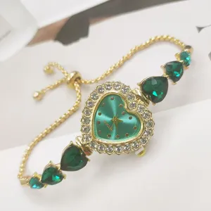 Detailansicht der goldenen Herz Strass Quarzuhr mit grünen Kristallen und verstellbarem Armband.