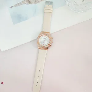 Vue détaillée de la montre à quartz tendance avec bracelet blanc et lunette étincelante.