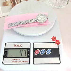 Detailansicht der Damen Strass Quarz-Armbanduhr mit Stahlband, Gewicht 47g auf der Waage.