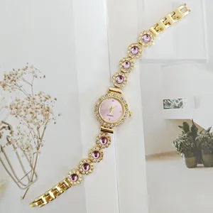 Detail der goldenen Quarz Damenarmbanduhr mit glänzenden Strasssteinen und lila Schmucksteinen.