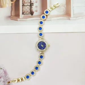 Goldene Damenuhr Detail mit blauen Strasssteinen und elegantem dunklen Zifferblatt.