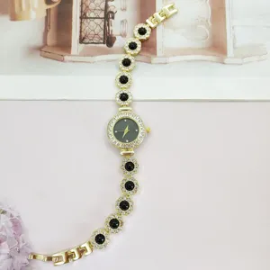 Elegante goldene Damen Quarzuhr mit glitzernden Strasssteinen und schwarzen Blumen Armband chic.