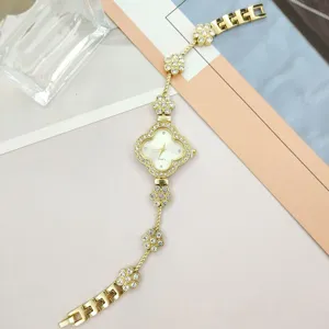 Close-up view of gold clover rhinestone women quartz watch detail, sparkling crystal bracelet.