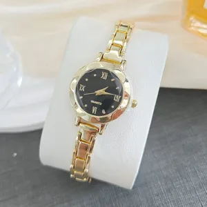 Montre quartz dorée pour femme avec cadran noir et bracelet en métal élégant détail.