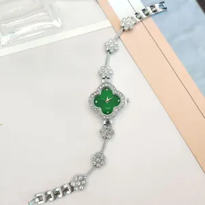 Close-up of the green four-leaf clover dial and sparkling rhinestone floral strap details.