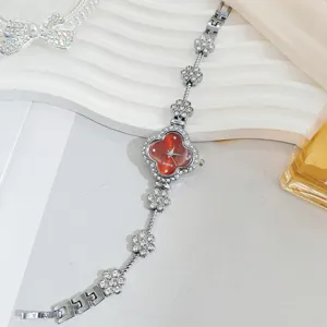 Close-up of red dial clover rhinestone watch band, shiny crystal details, elegant ladies accessory.