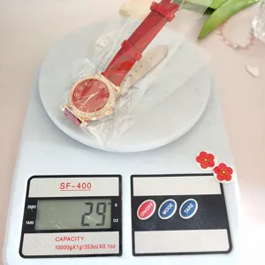 Detailed shot of red leather strap quartz watch with sparkling rhinestones on digital scale.