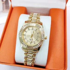 Goldfarbene Herren Quarz Uhr mit Zirkonia Steinen am Stahl Armband im orangen Etui Detail.