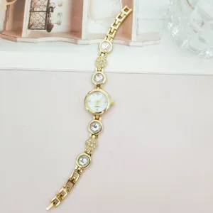 Nahaufnahme einer luxuriösen goldenen Damen Quarz Armbanduhr mit funkelnden Kristallen.