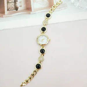 Detaillierte Nahaufnahme der eleganten goldenen Damen Quarz Armbanduhr mit schwarzen Steinen.