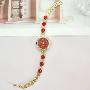 Detailansicht Damen Quarzuhr Armbanduhr mit roten Strasssteinen und goldenem Metallarmband.
