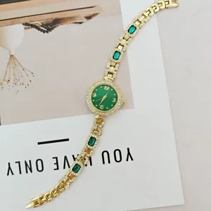Elegante goldene Damen-Quarzuhr mit grünen Edelsteinen und funkelnden Strasssteinen am Armband.