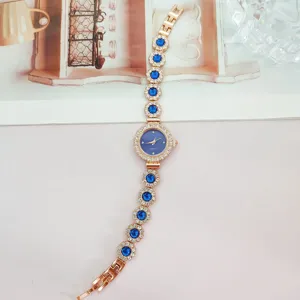 Roségoldfarbene Quarz-Armbanduhr mit blauen runden Edelsteinen und glänzenden Strasssteinen.