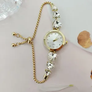 Nahaufnahme einer luxuriösen goldenen Damen Quarzurhr mit Herz Strasssteinen und Schiebekette.