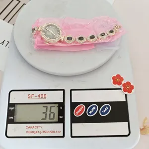 Detailansicht der Quarz-Armbanduhr mit Kleeblatt-Motiv und Strasssteinen auf der Waage.