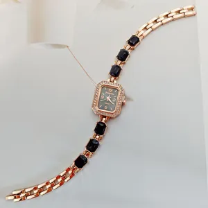 Orologio al quarzo da donna oro rosa con quadrante rettangolare, strass e bracciale nero.