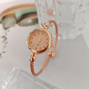 Vista detallada de un elegante reloj de pulsera de cuarzo en oro rosa con esfera clásica y banda.