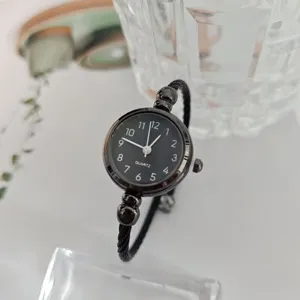 Reloj de pulsera de cuarzo minimalista con esfera negra para mujer, detalle elegante.