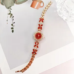 Damen Quarzarmbanduhr mit roten Kristallblüten, goldfarbenem Metallarmband und Zifferblatt.