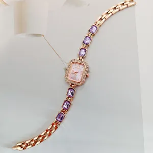 Dettaglio di un orologio al quarzo in oro rosa con bracciale in cristallo viola e quadrante.