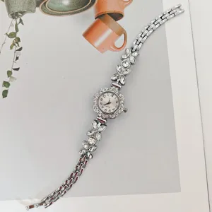 Damen Quarz Armbanduhr mit glitzernden Strassblumen und silberner Metallgliederarmband.