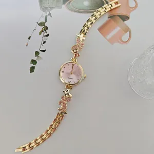 Elegante goldene Damenuhr mit Quarzwerk, rosafarbenen Strass-Schmetterlingen und Armband.
